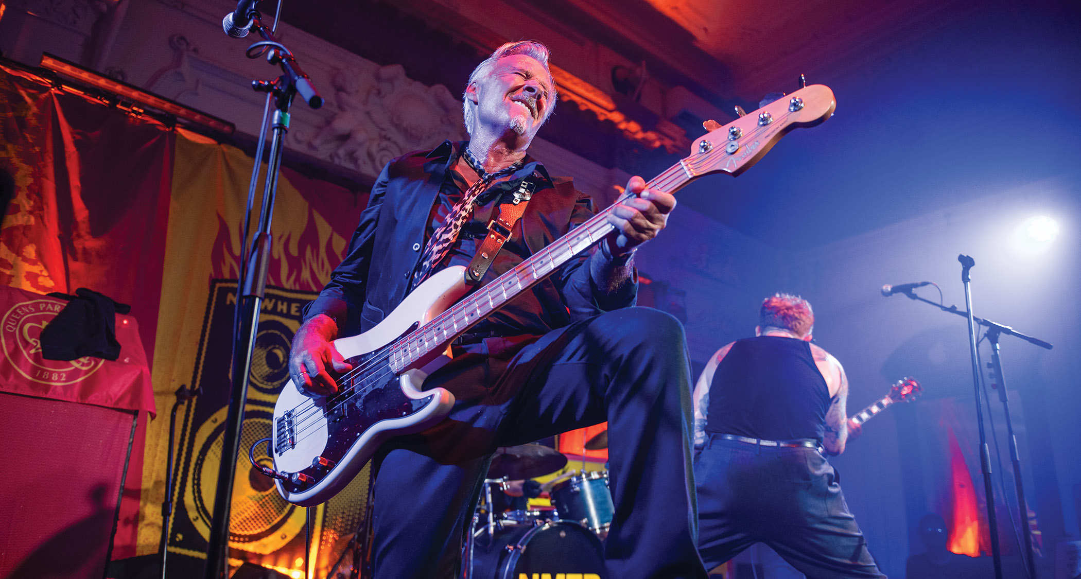 Sex Pistols bassist Glen Matlock smiles as he plays a Fender bass onstage.
