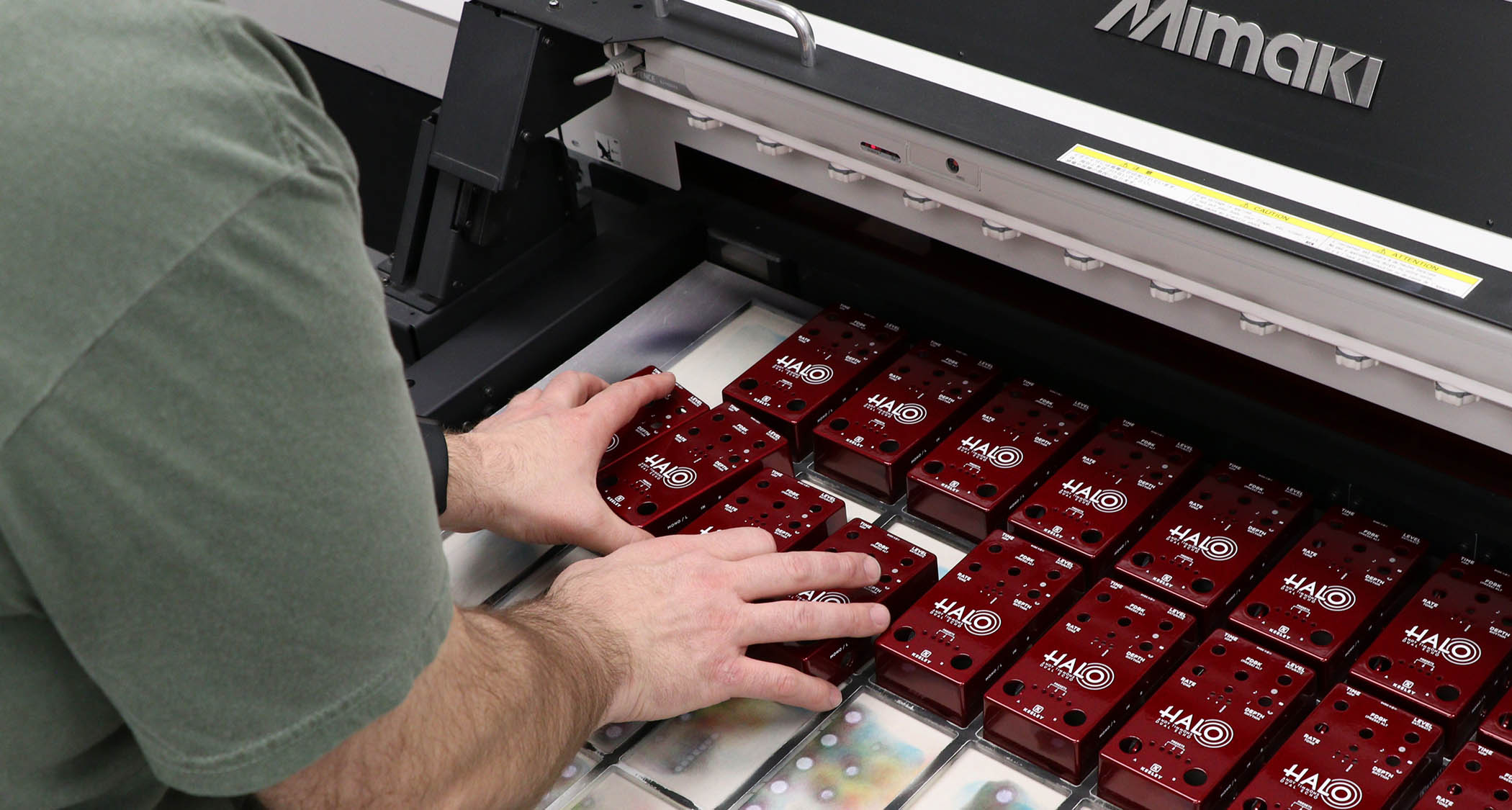 Derek Smith of Keeley Electronics loads Keeley pedals into a Mimaki UV printer as a new batch of Andy Timmons signature Halo delay pedal is made.