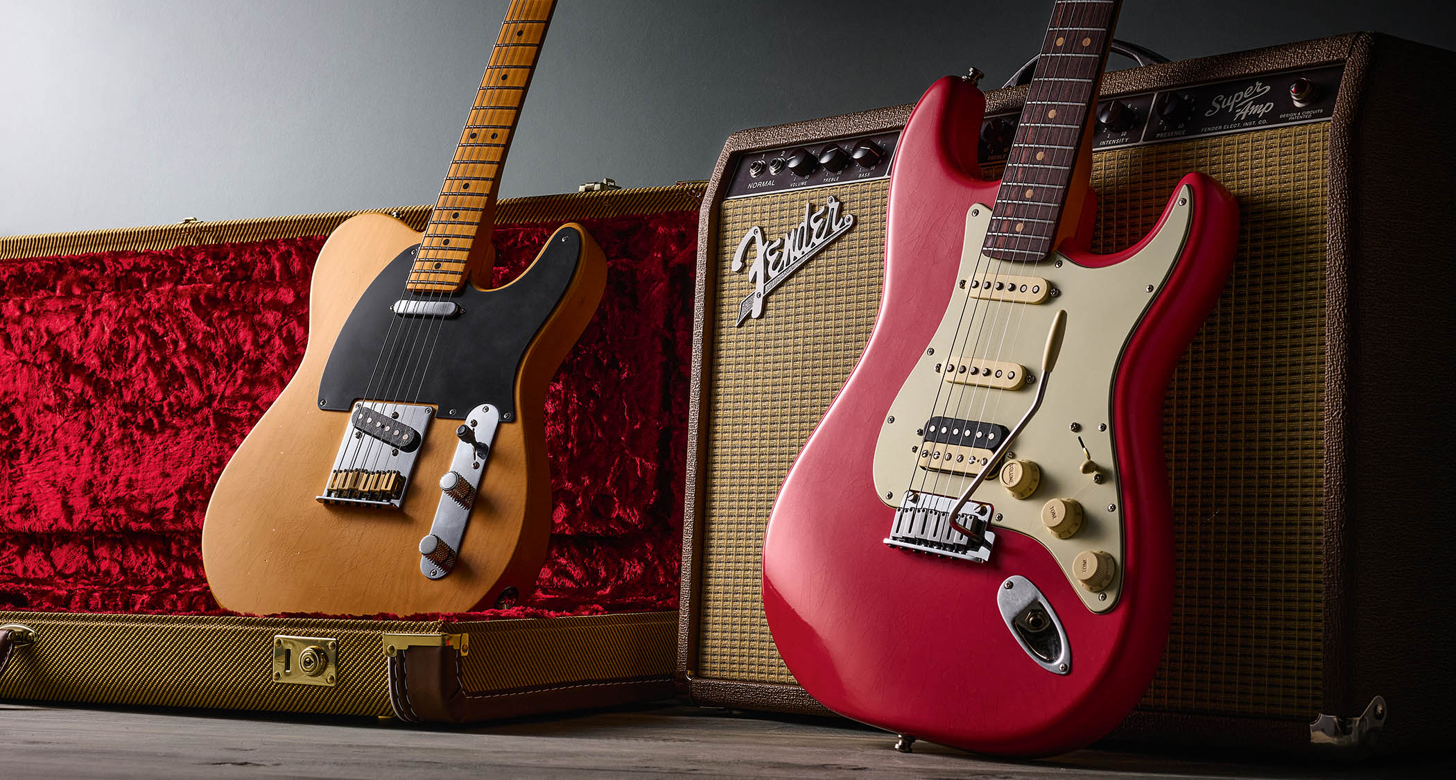 Fender American Ultra Luxe Vintage '50s Telecaster and Vintage '60s Stratocaster HSS photographed against a Fender combo and their tweed-covered case.