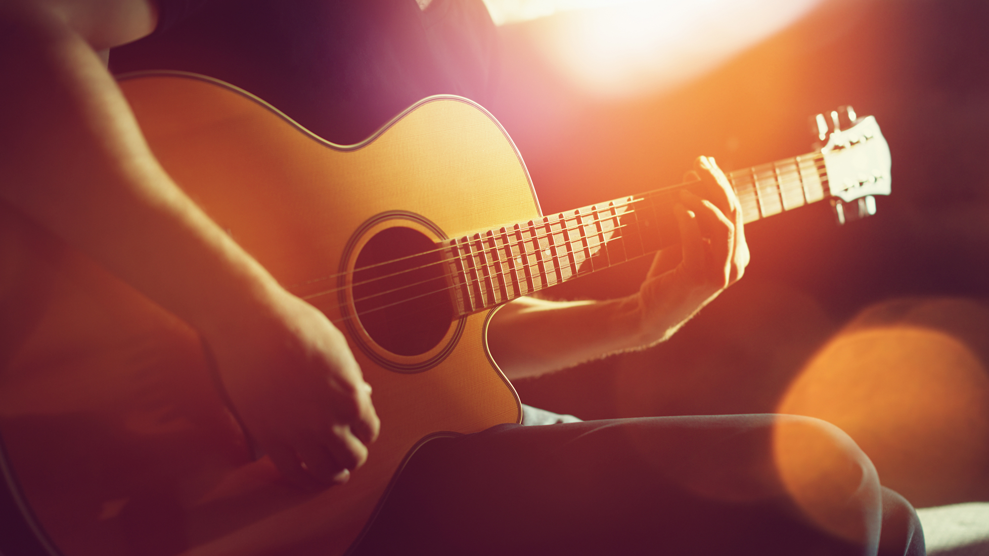 Guitarist playing an acoustic guitar in the sun